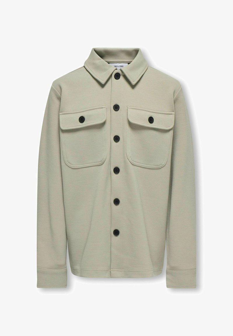 Giacca camicia a maniche lunghe color beige chiaro realizzata in tessuto texturizzato, con colletto a punta, due tasche sul petto e bottoni neri.