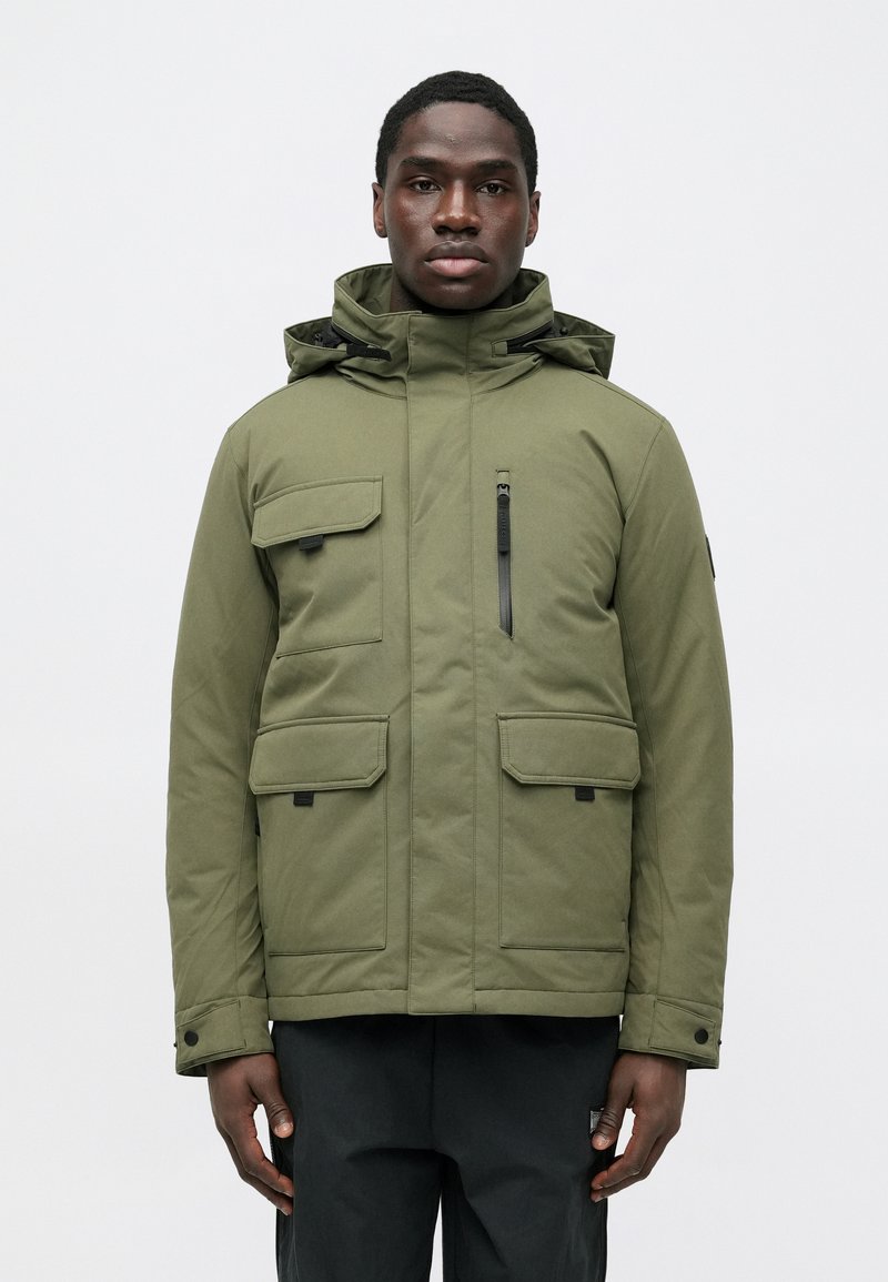 Olivgrüne Parka-Jacke mit Kapuze, verfügt über vier Fronttaschen, eine Reißverschlusstasche auf der Brust und schwarze Reißverschlussdetails. Glatte Textur.