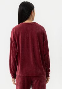 Bordeaux, lange mouw pullover gemaakt van zachte, gestructureerde stof. Heeft een ontspannen pasvorm met een ronde halslijn en verlaagde schouders.