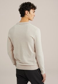 Pulover bej din tricot, cu mâneci lungi și tiv cu rebrare. Dispune de o guler clasic și o textură netedă. Vedere din spate.