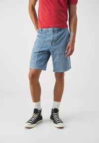 Heledad sinine denim lühikesed püksid, millel on mugav lõige, ees ja külgedel on taskud. Kombineeritud punase särgi ja mustade kõrgete tossudega.