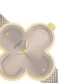 Montre à quartz avec un cadran en forme de papillon gris, accents dorés et bracelet en maille. Présente des aiguilles dorées et un petit logo au centre.