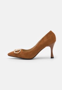 Bruna mockaskinn högklackad pump med spetsig tå, guldspänne på ovandelen och en svängd brun klack med svart bas.