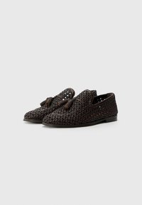 Brown woven loafers with a textured design, featuring a smooth toe and decorative tassels on the front. Flat sole and subtle accents.