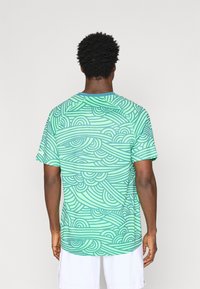 Μπλούζα κοντό μανίκι σε ανοιχτό πράσινο χρώμα με κυματιστές ριγέ σχέσεις. Κατασκευασμένη από ελαφρύ ύφασμα, διαθέτει λαιμόκοψη τύπου crew και κανονική εφαρμογή.