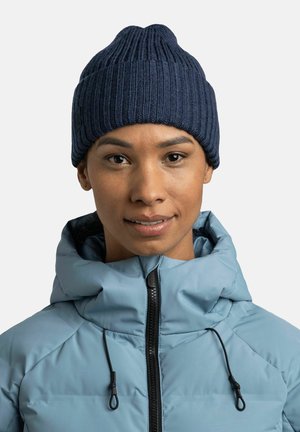 Navy ribbed knit beanie with a pointed top, paired with a light blue zip-up jacket featuring a high collar and drawstring accents.