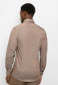 Brown button-up shirt with long sleeves, tailored fit, smooth texture, and a traditional collar, shown from the back against a white background.