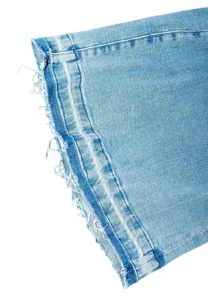 Lichtblauwe spijkerbroekspijp met rafelige, onafgewerkte zoom en zichtbare dubbele stiknaad langs de zijkant.