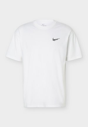 T-shirt blanc à manches courtes et col rond avec petit logo noir Nike swoosh sur la poitrine gauche, présenté sur un fond uni.