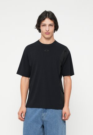 T-shirt nera a maniche corte con collezione rotonda, caratterizzata da un logo discreto sul petto e pannelli laterali in tessuto testurizzato. Realizzata in un tessuto leggero.