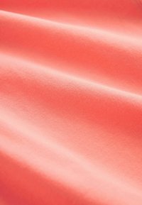 Tessuto color corallo con una consistenza liscia, caratterizzato da morbide pieghe drappeggiate e un aspetto uniforme, che mette in evidenza la sua leggerezza.