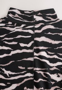 Haut en tissu côtelé noir avec un motif de rayures tigre rose clair, doté d'un col montant et d'un dos sans coutures.