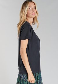 T-shirt noir à manches courtes avec une coupe décontractée, fabriqué en tissu doux. Texture lisse et design simple, avec un col rond.