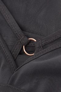 Černá síťovaná látka s hladkým povrchem, zdobená kovovým růžově zlatým kruhem a kontrastním stehem. Kompaktní a funkční design.