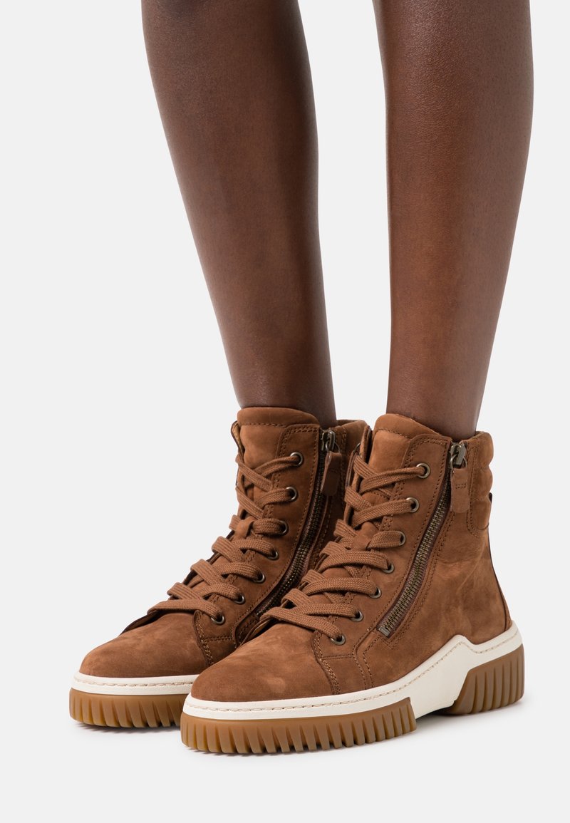 Bruna mockasin höga stövlar med en kraftig vit sula, har metalldragkedjefinter och snörning fram. Strukturert finish och hög topp-design.