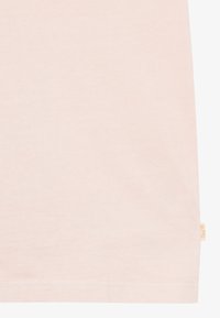 Tricou din bumbac roz deschis, cu o textură netedă, mâneci scurte și un eticheta mică de marcă pe partea stângă, aproape de margine.