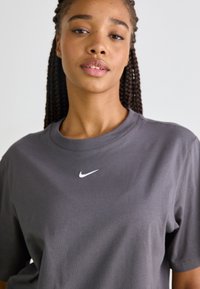 Grå bomull T-skjorte med rund hals og korte ermer, med en liten hvit Nike-logo sentrert på brystet.