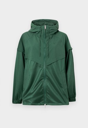 Zaļa sporta jaka ar pilnu rāvējslēdzēju, kapuci ar auklu, elastīgiem aprocēm un kontrastējošiem paneļiem. Izgatavota no gluda, viegla materiāla.