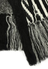 Écharpe tissée noire et blanche avec des franges, présentant un mélange de textures et de motifs, y compris des sections tricotées et des motifs audacieux.
