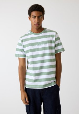 Groen en wit gestreept T-shirt met een ronde hals en het logo "GUESS JEANS" aan de voorkant. Gemaakt van katoen, heeft korte mouwen en een relaxte pasvorm.