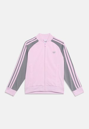 Geacă sport Adidas roz deschis cu fermoar, mâneci gri cu dungi roz și logo Adidas pe piept.