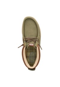 Zapatilla de lona verde oliva con acentos marrones, puntera redonda y cordones elásticos. El interior presenta un patrón de cuadro y un forro acolchado.