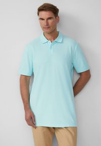 Lichtblauwe polo van katoen, met een klassieke kraag, korte mouwen en een subtiel logo op de borst. Glad oppervlak.