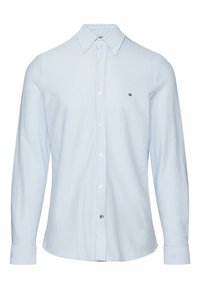 Camisa a rayas de color azul claro, hecha de algodón, con cuello button-down, mangas largas y un pequeño logo sobre el bolsillo izquierdo del pecho.