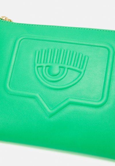 Green leather pouch featuring an embossed eye design in a speech bubble shape, with a gold zipper pull detail. Smooth texture.