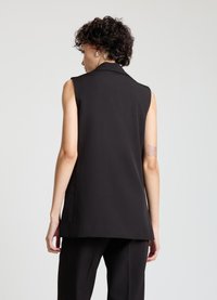Gilet noir sans manches avec un col profond, un design élégant et une texture lisse, présentant une coupe droite qui dépasse la taille.