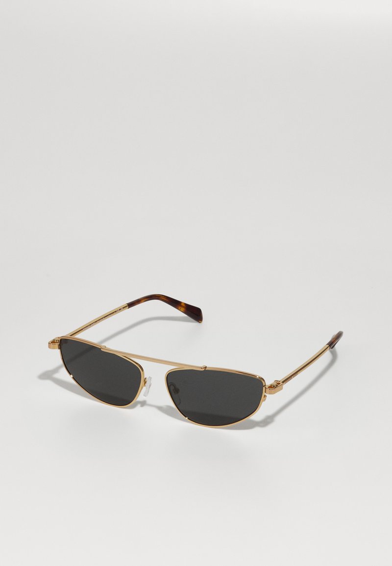 Gafas de sol de metal dorado con lentes oscuros, con una forma angular única y brazos de carey marrón. Almohadillas nasales transparentes para mayor comodidad.