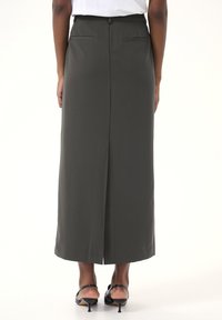 Maxi-Rock aus dunkelgrauem Stoff, mit gerader Silhouette, Gesäßtaschen und einem mittigen Schlitz für optimalen Bewegungsfreiraum.
