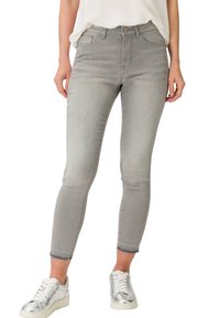 Šedé skinny džíny s mírným odřením, mají pět kapsových design, zapínání na knoflík vepředu a zkrácené nohavice. Kombinované se stříbrnými teniskami.