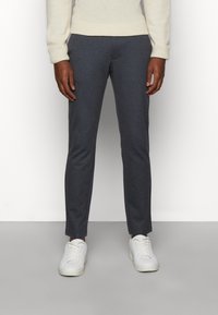 Pantaloni tailored a quadri grigi realizzati in tessuto morbido, con una vestibilità slim. Indossati con sneakers bianche e un maglione crema.