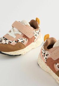 Børnesneakers med beige, brune og lyserøde leopardprintdetaljer, hvide snøringer, velcrostropper og spraglet cremefarvet sål på en hvid baggrund.