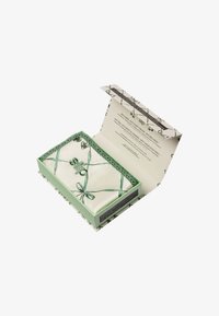 Scatola regalo con un interno verde menta, prodotto avvolto in seta bianca con un nastro verde abbinato e imballaggio esterno decorato.