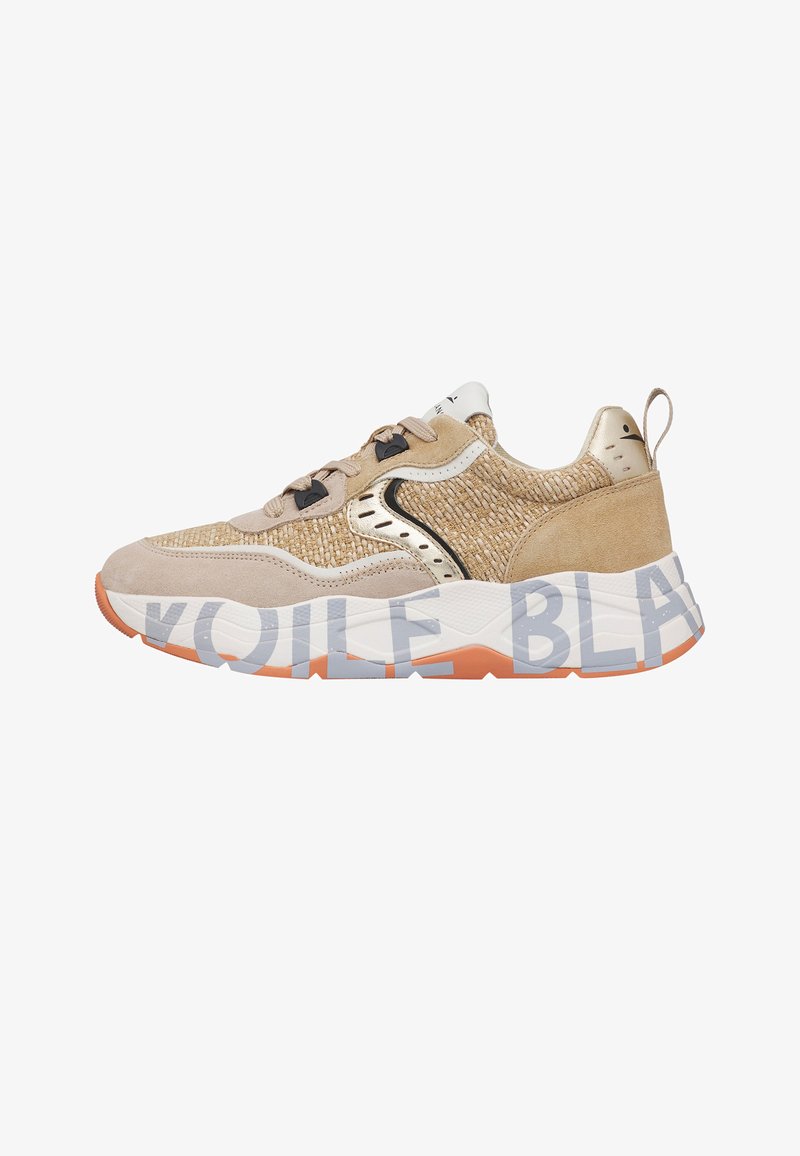 Zapatilla beige y canela con textura tejida, detalles en ante, suela blanca con grandes letras grises parciales y detalles en la suela externa de color naranja.