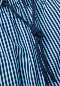 La tela a rayas en azul marino y azul claro presenta una cinturilla elástica con un cordón trenzado y puntas de plástico para asegurar un buen ajuste.