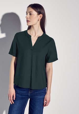 Blusa verde scuro a maniche corte con vestibilità rilassata, caratterizzata da un colletto a V e maniche arrotolate. Tessuto liscio senza pattern visibili.
