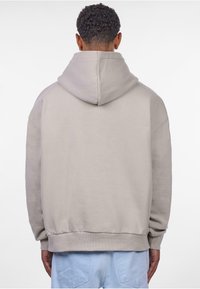 Hellgrauer Kapuzenpullover mit großer Kapuze, gerippten Bündchen und lockerer Passform. Weiches Baumwollmischgewebe mit glatter Textur.