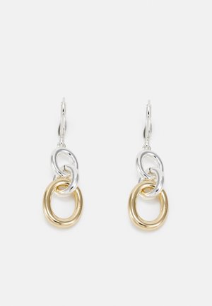 Boucles d'oreilles pendantes en argent et or avec deux boucles ovales entrelacées, une en argent et une en or, sur fond blanc.