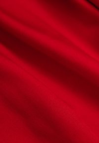 Gładka czerwona tkanina z delikatnym połyskiem; widoczne zagięcia i tekstura sugerują lekką strukturę, odpowiednią do drapowania lub odzieży.