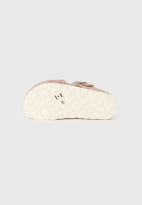 Rosa textilsko sko med en texturerad yta, utrustad med ett kardborreband och en vadderad, vit gummisula med ett mönster. Storlek synlig: 26.