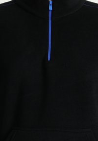 Sudadera de poliéster negro con media cremallera en azul. Presenta un alto cuello y un bolsillo frontal, destacando su textura suave.