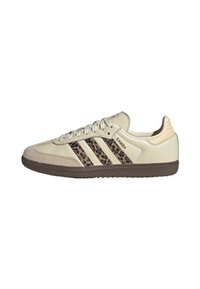 Sneakers w kolorze brązowym i kremowym, wykonane z zamszu i skóry, z trzema brązowymi paskami w kwiatowy wzór oraz teksturowaną brązową podeszwą.