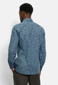 Blaues, floral gemustertes Hemd mit Tailored Fit, langen Ärmeln und standardisiertem Kragen, das verschiedene kleine Blumendesigns zeigt.