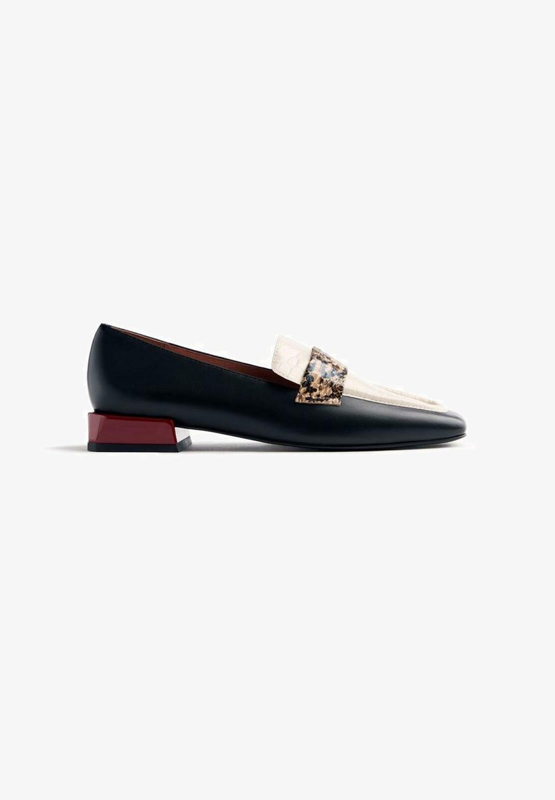 Mocassin en cuir noir avec un accent crème et à motifs imprimés, doté d'un talon rouge triangulaire et d'un design lisse et élégant.