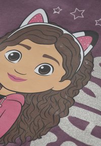 Cartoonfigur mit lockigem braunem Haar, die einen pinken Hoodie trägt, vor einem lila Hintergrund mit Sternakzenten und metallisch silbernem Text.
