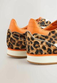Leopardmuster Sneakers mit orangefarbenen Lederakzenten, texturiertem Fellobermaterial, weißen Schnürsenkeln und einer leichten Gummisohle mit strukturiertem Profil.