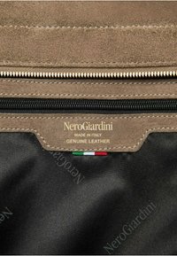Bustina in vera pelle con esterno in morbido suede, dotata di una cerniera nera, logo dorato e un piccolo dettaglio con il tricolore italiano.